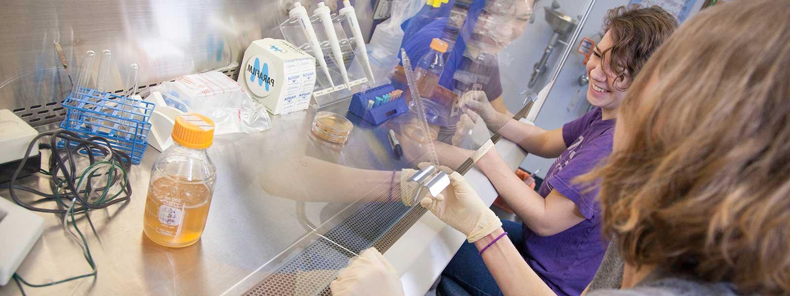 student smiles while working in microbiology lab